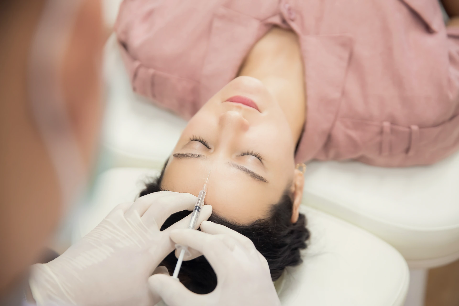 Young woman getting beauty facial injections in salon. Beautician makes cosmetic injection into the patient face frown lines. Beauty injections, mesotherapy, revitalization and rejuvenation