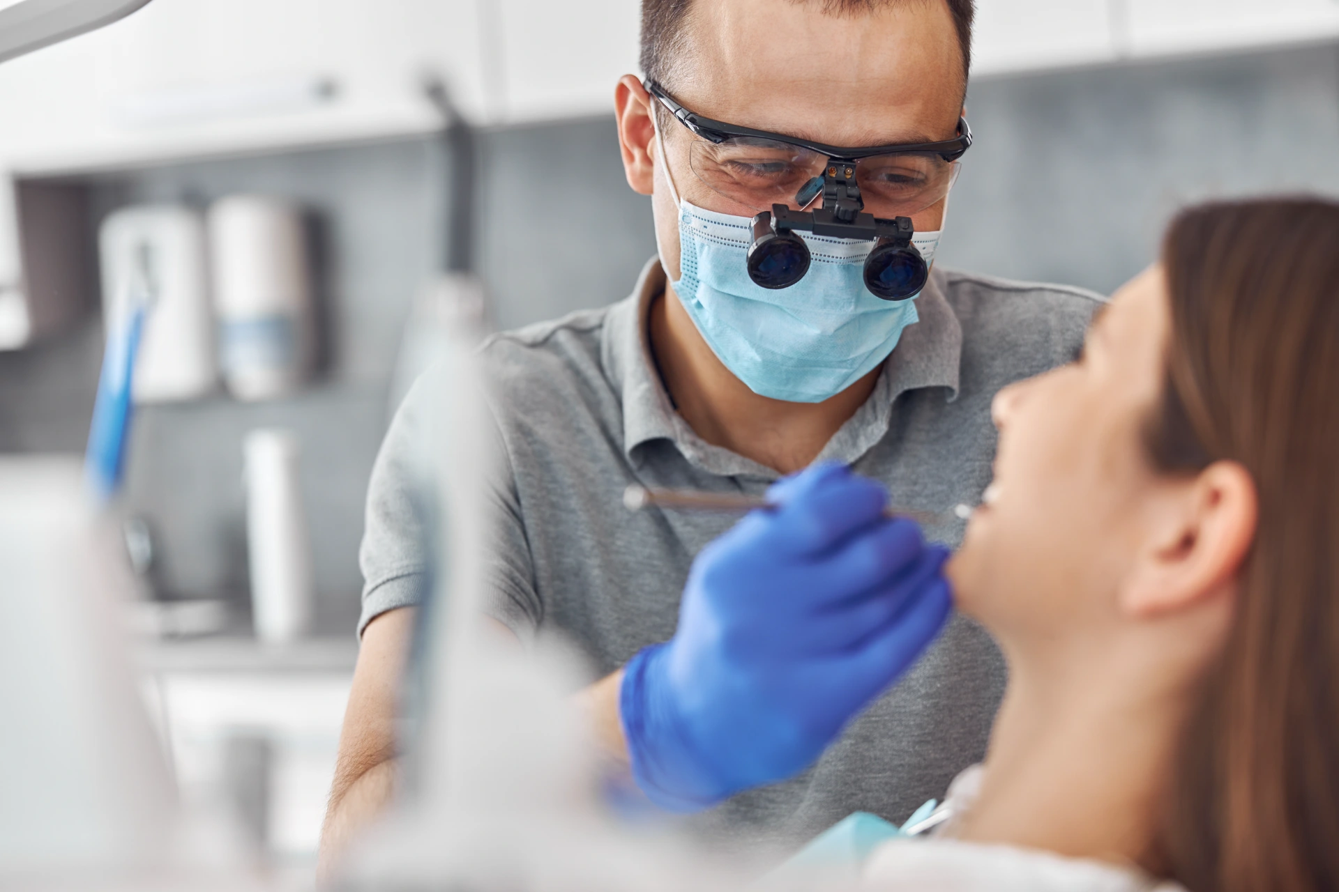 Modern dental surgery, face of a female doctor working on a patient. Dental implantation operation on a patient at dentistry office