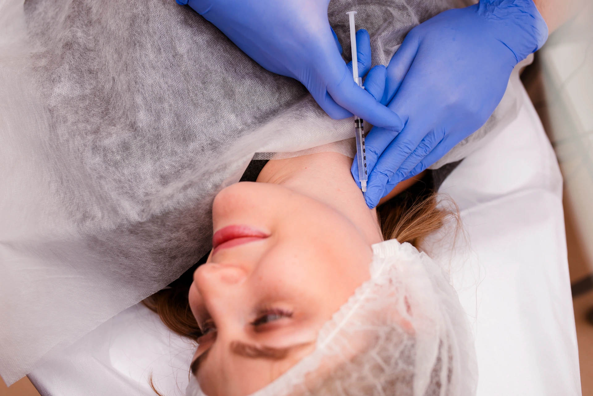 Beautician doctor with botulinum toxin syringe making injection to platysmas bands.Neck rejuvenation mesotherapy.Anti-aging treatment and face lift in cosmetology clinic.Patient lying on chair.