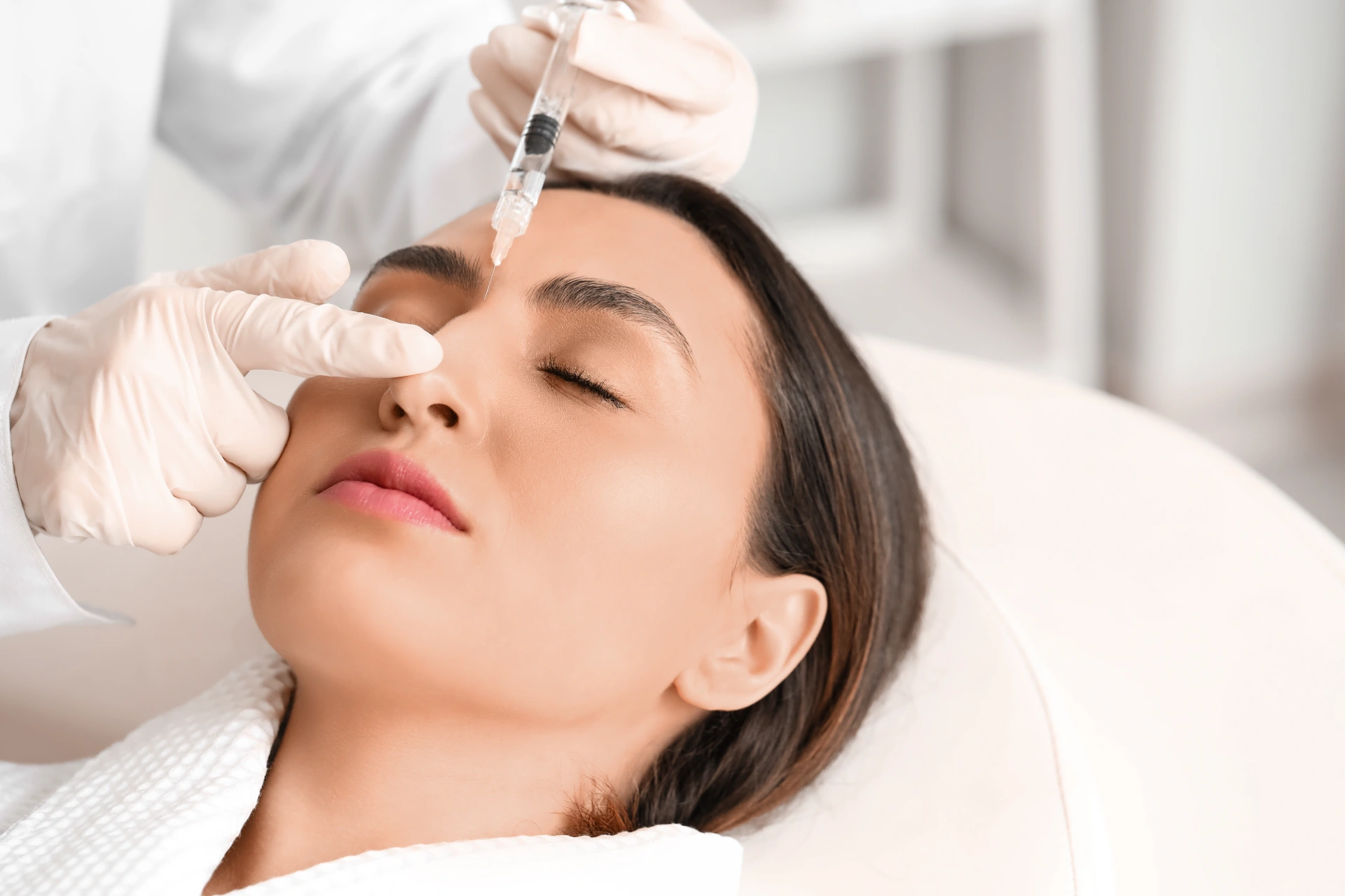 Young woman receiving filler injection in beauty salon