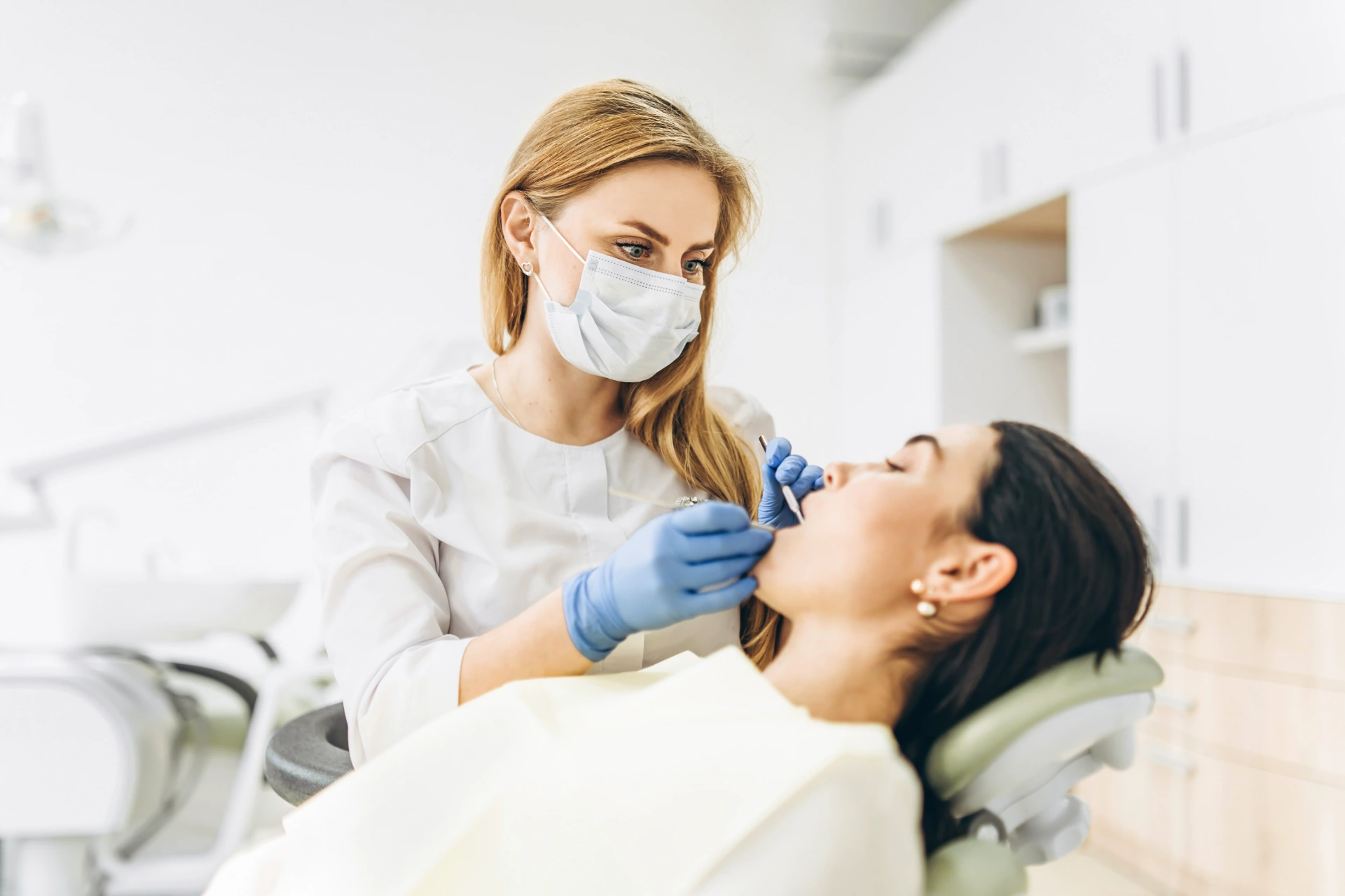 Female dentist with female patient in dental chair providing oral cavity treatment