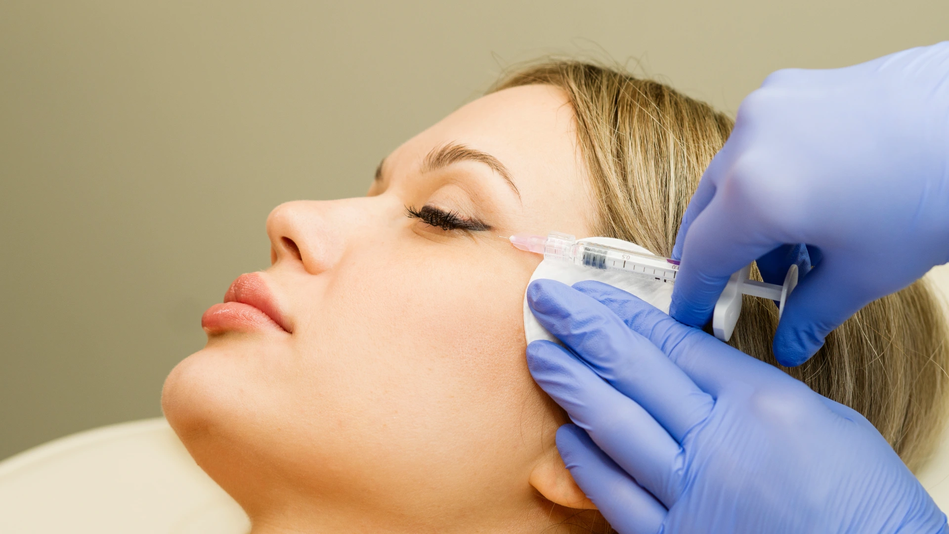 Face skin rejuvenation mesotherapy injection for female patient. Anti-aging treatment in cosmetology clinic. Beautician's hand in gloves with syringe. Smoothing of periorbital wrinkles "crow's feet"