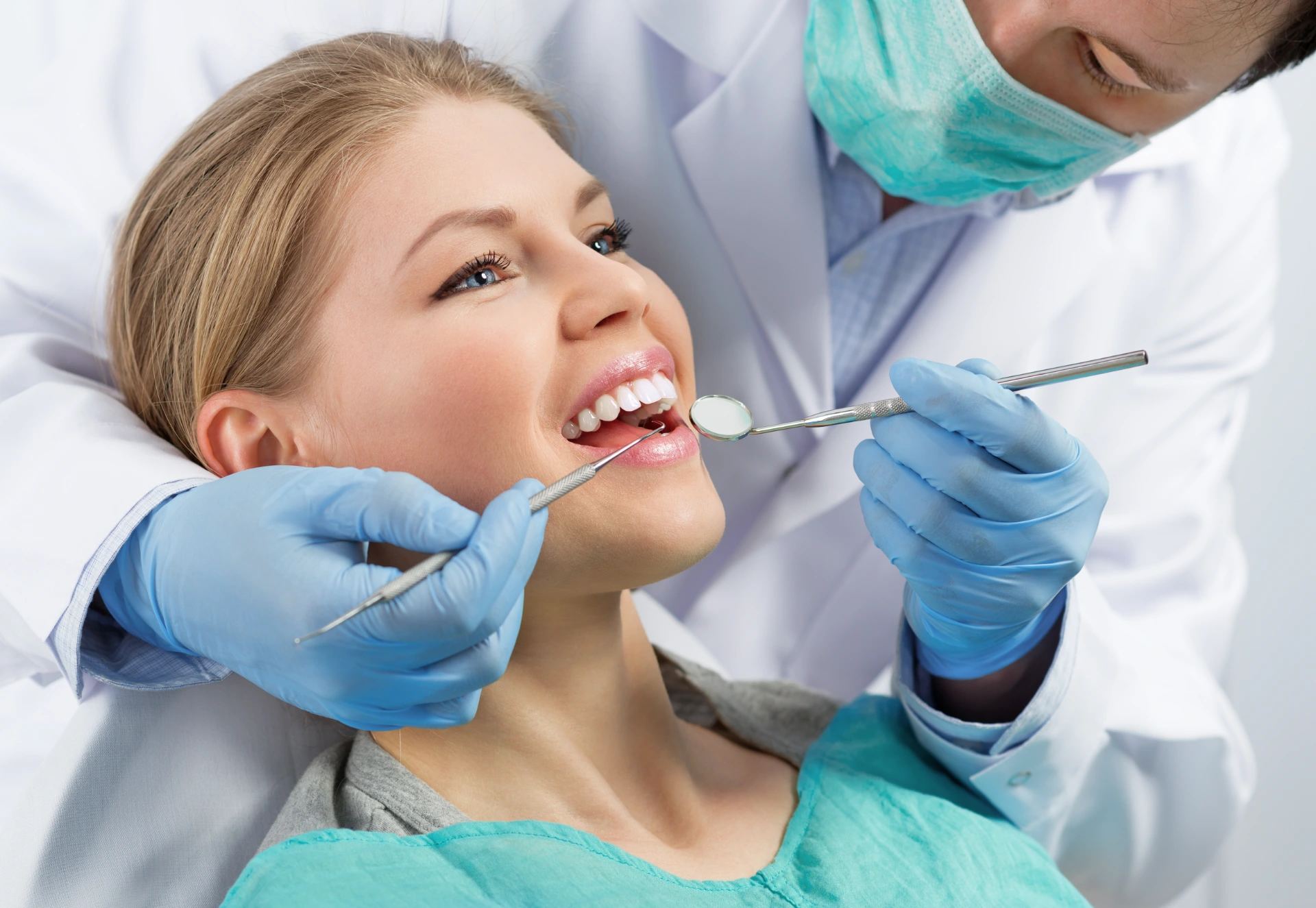 Gingivitis therapy. Male surgeon examining female's molar before treatment in dental clinic.